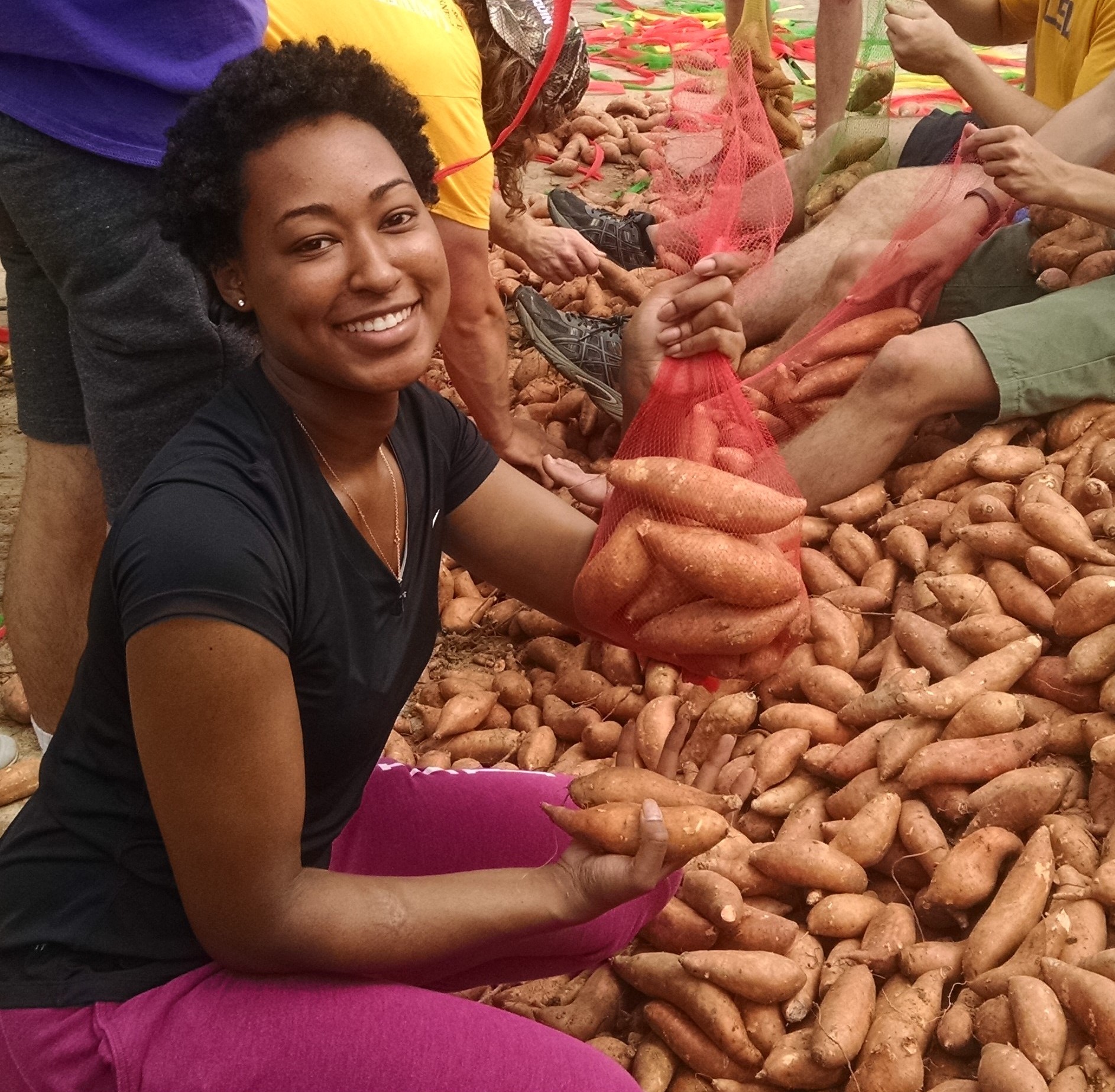 Volunteer holding a bag of Sweet Potatoes